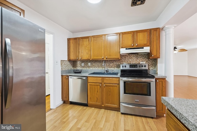 6775 Amherst Rd, Bryans Road, MD 20616 - kitchen featuring stainless steel appliances, under cabinet range hood, a sink, ornate columns, and light wood-style flooring