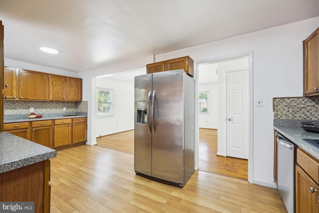 6775 Amherst Rd, Bryans Road, MD 20616 - kitchen with appliances with stainless steel finishes, light wood-type flooring, decorative backsplash, brown cabinets, and dark countertops