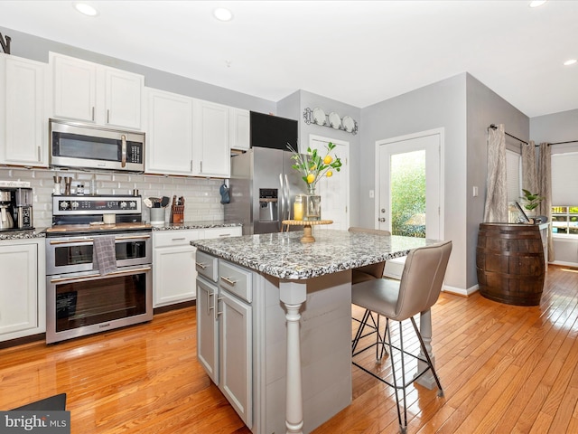 1501 Rambling Way, Frederick, MD 21701 - kitchen with stainless steel appliances, a kitchen breakfast bar, light wood finished floors, decorative backsplash, and light stone countertops