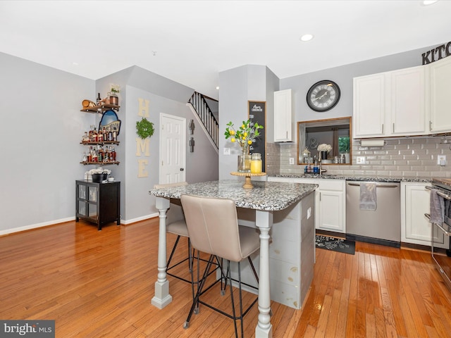1501 Rambling Way, Frederick, MD 21701 - kitchen with stainless steel dishwasher, a kitchen breakfast bar, white cabinets, decorative backsplash, and light wood-type flooring