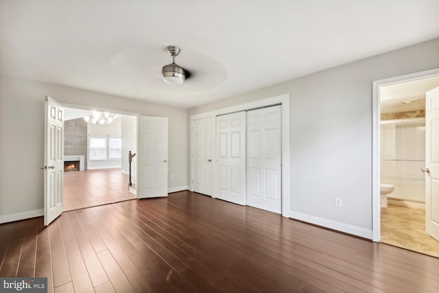 810 Sugarland Run Dr, Sterling, VA 20164 - unfurnished bedroom with dark wood-style flooring, baseboards, a chandelier, ensuite bath, and a tile fireplace