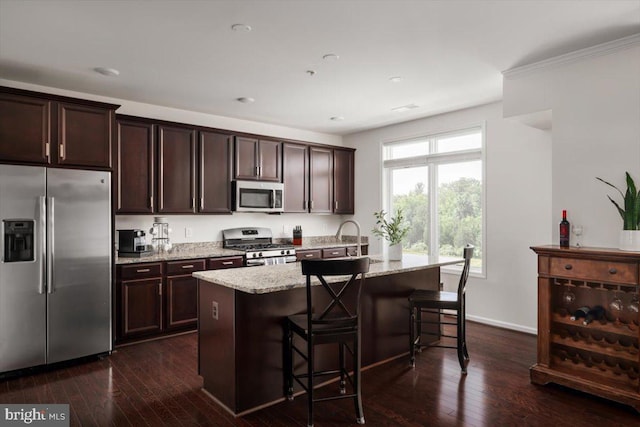 1318 Ribbon Limestone Ter SE, Leesburg, VA 20175 - kitchen with stainless steel appliances, an island with sink, dark brown cabinetry, light stone countertops, and dark wood-style floors