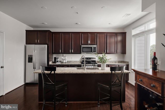 1318 Ribbon Limestone Ter SE, Leesburg, VA 20175 - kitchen featuring appliances with stainless steel finishes, light stone countertops, a kitchen breakfast bar, dark brown cabinetry, and dark wood-type flooring