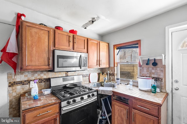 2348 N Mascher St, Philadelphia, PA 19133 - kitchen with stainless steel appliances, a sink, tile countertops, tasteful backsplash, and brown cabinets