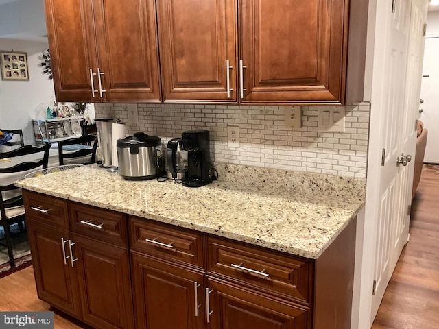 kitchen with wood finished floors, decorative backsplash, and light stone counters