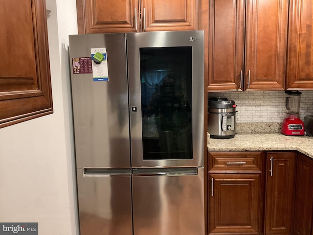 kitchen with freestanding refrigerator, tasteful backsplash, and light stone counters