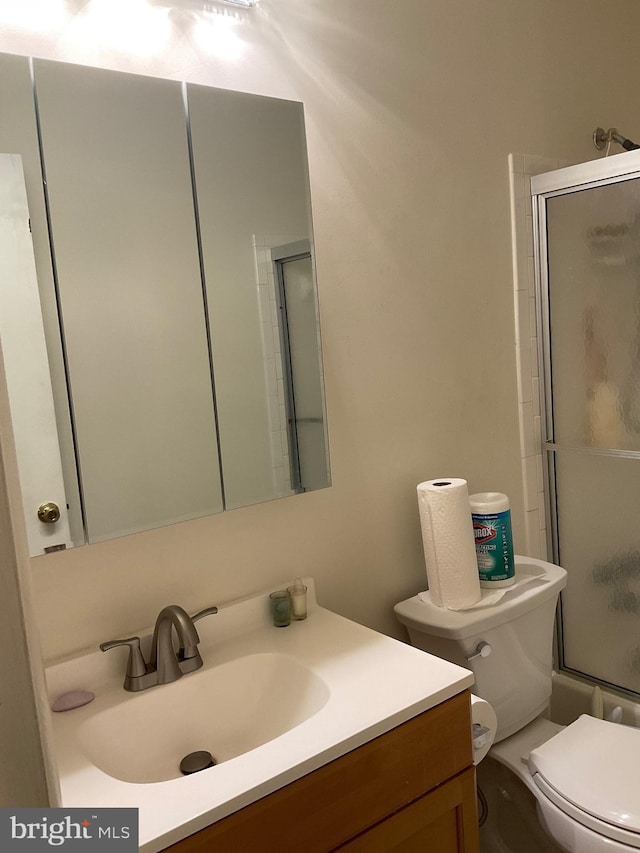 full bath with vanity, a shower with door, and toilet