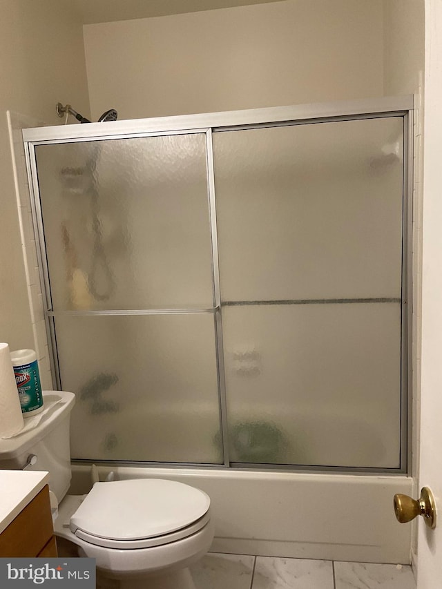 bathroom featuring marble finish flooring, toilet, vanity, and shower / bath combination with glass door