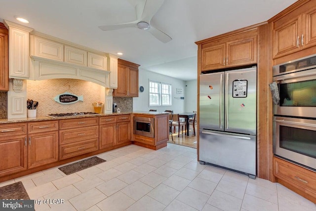 279 Apache Dr, Shickshinny, PA 18655 - kitchen featuring appliances with stainless steel finishes, a ceiling fan, backsplash, light stone counters, and brown cabinets