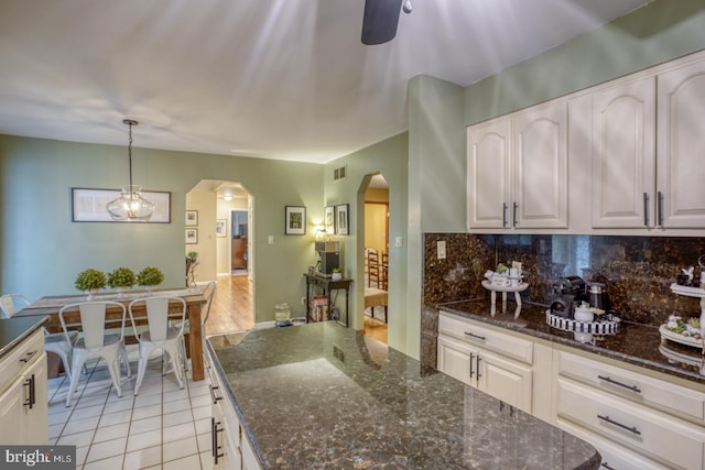 7857 Holly Branch Dr, Laurel, DE 19956 - kitchen featuring arched walkways, tasteful backsplash, light tile patterned floors, dark stone countertops, and pendant lighting