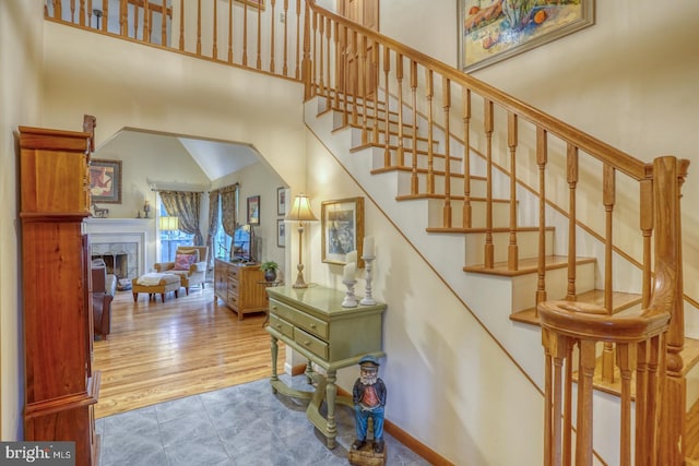 7857 Holly Branch Dr, Laurel, DE 19956 - stairs with a towering ceiling, a tiled fireplace, and baseboards