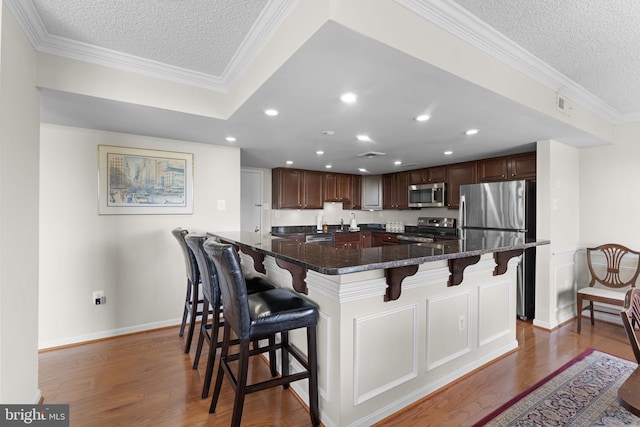 1515 S Arlington Ridge Rd Unit 402, Arlington, VA 22202 - kitchen with appliances with stainless steel finishes, a textured ceiling, wood finished floors, a kitchen bar, and recessed lighting