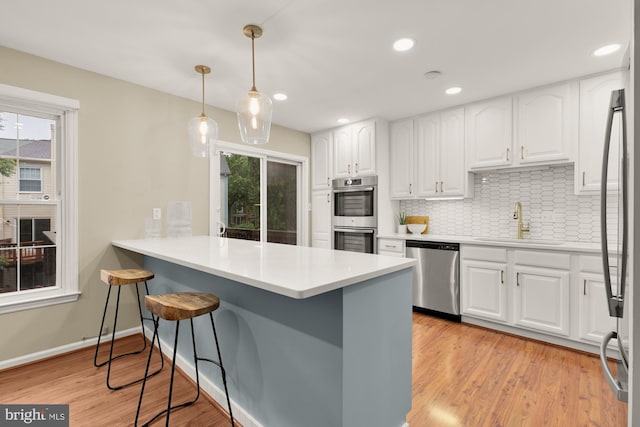 7504 Oldham Way, Alexandria, VA 22315 - kitchen with stainless steel appliances, a sink, a breakfast bar, a peninsula, and white cabinetry