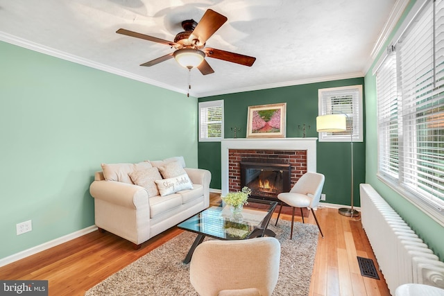 7906 Garland Ave, Takoma Park, MD 20912 - living room with wood finished floors, baseboards, a brick fireplace, a ceiling fan, and radiator
