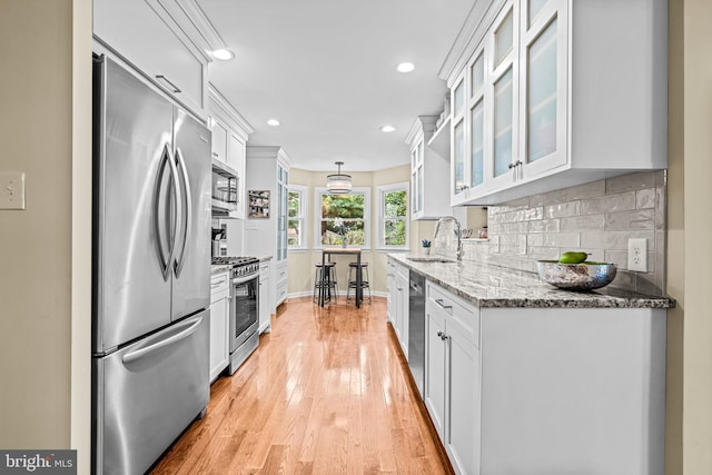 4047 Holly Way, Doylestown, PA 18902 - kitchen with stainless steel appliances, a sink, white cabinetry, decorative backsplash, and light wood-style flooring
