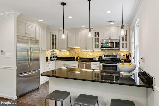 9212 E Parkhill Dr, Bethesda, MD 20814 - kitchen featuring appliances with stainless steel finishes, a peninsula, a breakfast bar, glass insert cabinets, and tasteful backsplash