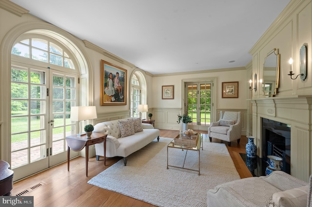 601 Maplewood Rd, Wayne, PA 19087 - living area with plenty of natural light, french doors, light wood finished floors, a fireplace with flush hearth, and wainscoting