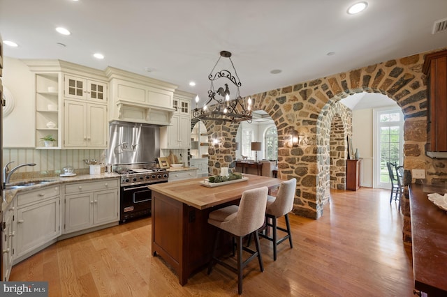 601 Maplewood Rd, Wayne, PA 19087 - kitchen featuring designer stove, arched walkways, a sink, light wood-type flooring, and a kitchen breakfast bar
