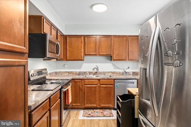 1931 Fort Monroe Ct, Dumfries, VA 22026 - kitchen with stainless steel appliances, brown cabinetry, light wood finished floors, and light stone counters