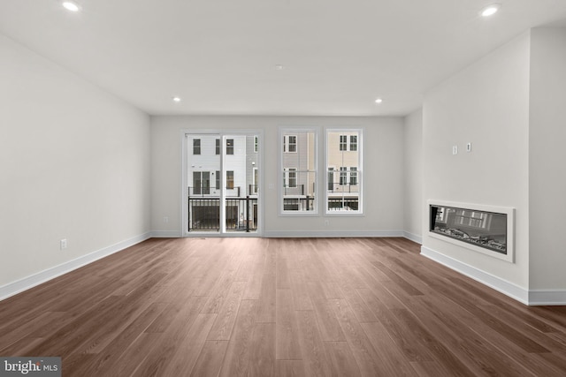 23062 Soaring Heights Ter, Ashburn, VA 20148 - unfurnished living room featuring a glass covered fireplace, wood finished floors, baseboards, and recessed lighting