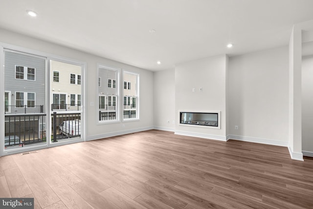 23062 Soaring Heights Ter, Ashburn, VA 20148 - unfurnished living room featuring wood finished floors, baseboards, recessed lighting, and a glass covered fireplace