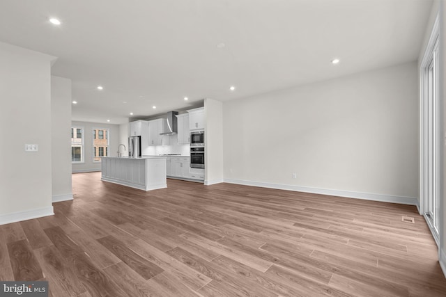 23062 Soaring Heights Ter, Ashburn, VA 20148 - unfurnished living room with light wood-style floors, recessed lighting, and baseboards