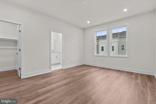 23062 Soaring Heights Ter, Ashburn, VA 20148 - unfurnished bedroom with light wood-style flooring, a spacious closet, baseboards, recessed lighting, and connected bathroom