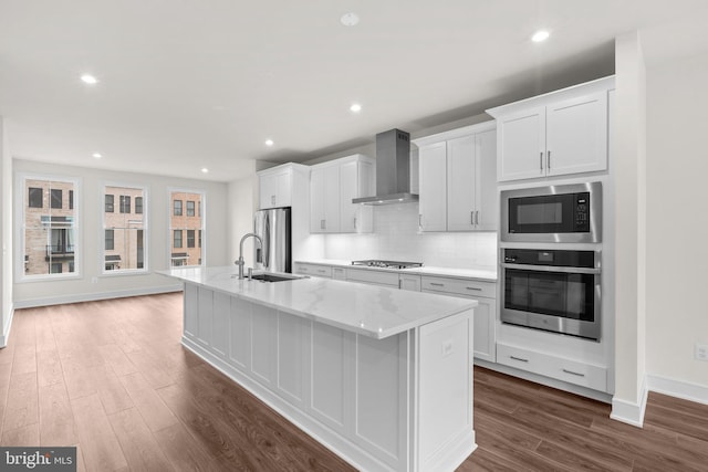 23062 Soaring Heights Ter, Ashburn, VA 20148 - kitchen featuring appliances with stainless steel finishes, wall chimney range hood, a sink, a kitchen island with sink, and white cabinets