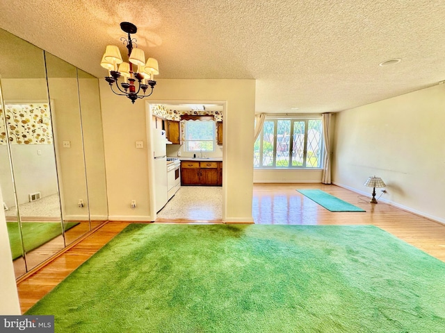 8128 Lister St, Philadelphia, PA 19152 - unfurnished dining area with a sink, light wood-style flooring, a chandelier, a textured ceiling, and baseboards