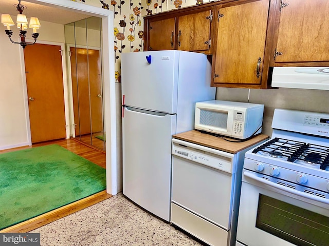 8128 Lister St, Philadelphia, PA 19152 - kitchen with white appliances, exhaust hood, a chandelier, brown cabinets, and wallpapered walls
