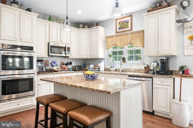 550 Long Meadow Dr, Fredericksburg, VA 22406 - kitchen with appliances with stainless steel finishes, dark wood-style flooring, a kitchen island, a breakfast bar, and recessed lighting
