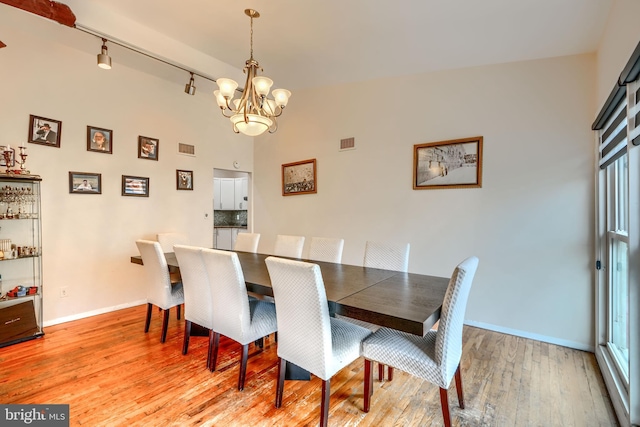 2409 Lightfoot Dr, Baltimore, MD 21209 - dining room featuring a chandelier, track lighting, light wood finished floors, baseboards, and a high ceiling