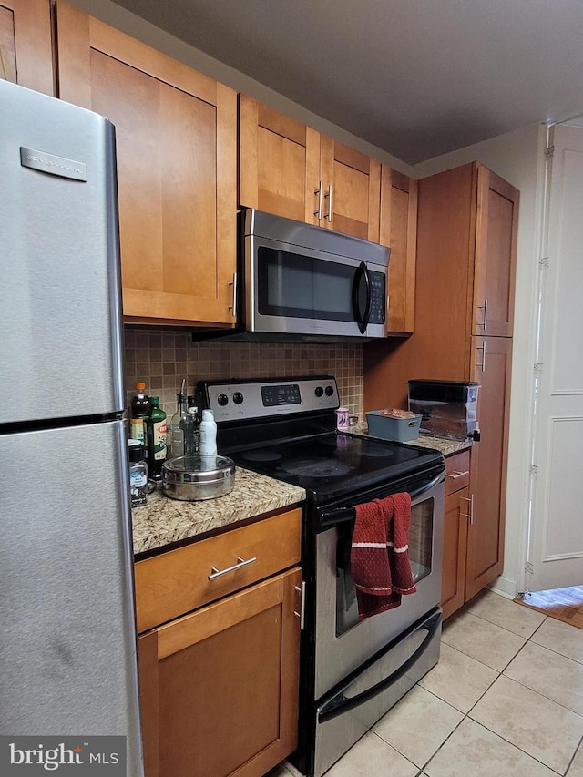 224 W Rittenhouse Sq Unit 2701, Philadelphia, PA 19103 - kitchen featuring stainless steel appliances, tasteful backsplash, light tile patterned flooring, and brown cabinetry