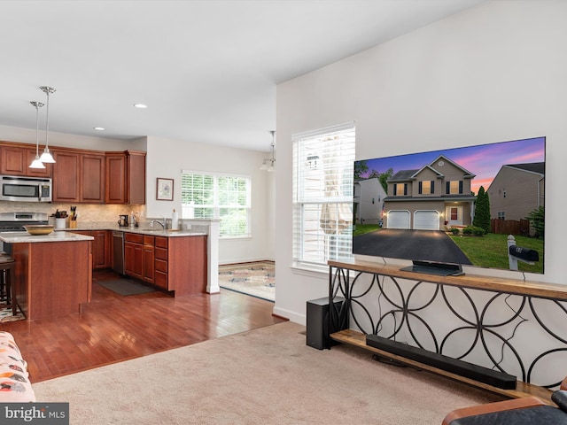 83 Clarence Ave, Severna Park, MD 21146 - kitchen with stainless steel appliances, carpet flooring, light countertops, brown cabinetry, and decorative light fixtures