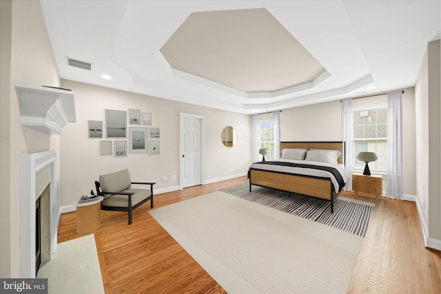 1 Derbyshire Way, Wilmington, DE 19807 - bedroom featuring a tray ceiling, a fireplace with flush hearth, light wood-style floors, and recessed lighting