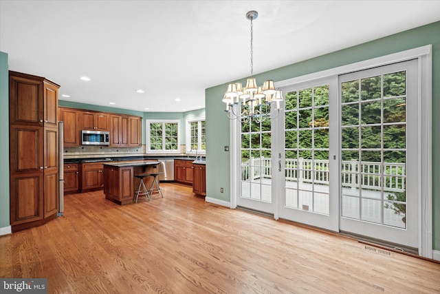1 Derbyshire Way, Wilmington, DE 19807 - kitchen with appliances with stainless steel finishes, dark countertops, a chandelier, light wood finished floors, and brown cabinetry