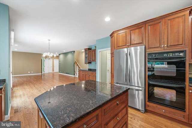 1 Derbyshire Way, Wilmington, DE 19807 - kitchen with freestanding refrigerator, a chandelier, brown cabinets, light wood-type flooring, and dark stone countertops