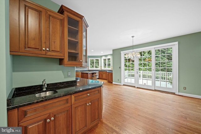 1 Derbyshire Way, Wilmington, DE 19807 - kitchen with brown cabinetry, light wood-type flooring, a chandelier, dark stone counters, and glass insert cabinets