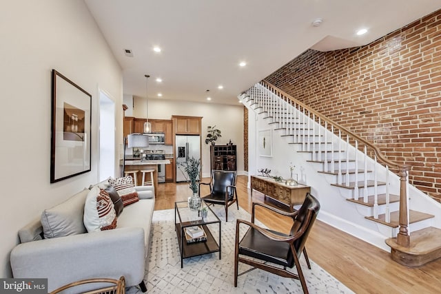 251 8th St NE, Washington, DC 20002 - living room with stairway, light wood-style flooring, brick wall, baseboards, and recessed lighting
