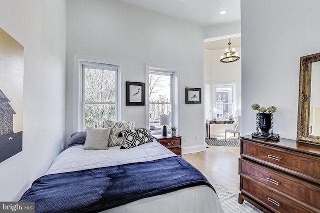 251 8th St NE, Washington, DC 20002 - bedroom with a chandelier, light wood-style flooring, connected bathroom, a high ceiling, and baseboards