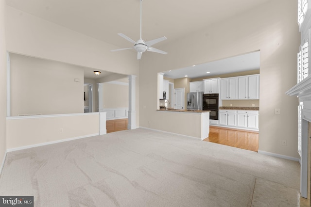 327 Astilbe Dr, Kennett Square, PA 19348 - unfurnished living room featuring light colored carpet, a ceiling fan, a sink, a fireplace, and baseboards