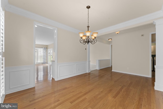 327 Astilbe Dr, Kennett Square, PA 19348 - empty room with a chandelier, light wood finished floors, a wainscoted wall, crown molding, and a decorative wall