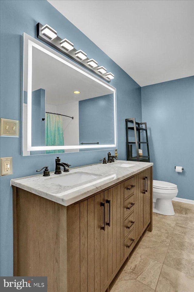 701 Antietam Dr, Douglassville, PA 19518 - bathroom featuring double vanity, toilet, baseboards, stone finish flooring, and a shower with shower curtain