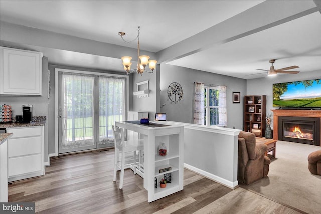 701 Antietam Dr, Douglassville, PA 19518 - dining area with light wood-style flooring, a chandelier, a glass covered fireplace, a ceiling fan, and baseboards