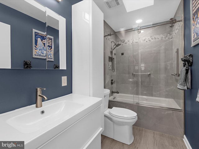 9112 Chesapeake Ave, Sparrows Point, MD 21219 - full bathroom with shower / bath combination with glass door, wood finished floors, vanity, toilet, and a skylight