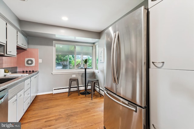 10400 Conover Dr, Silver Spring, MD 20902 - kitchen with stainless steel appliances, a baseboard radiator, decorative backsplash, light wood-style floors, and white cabinets