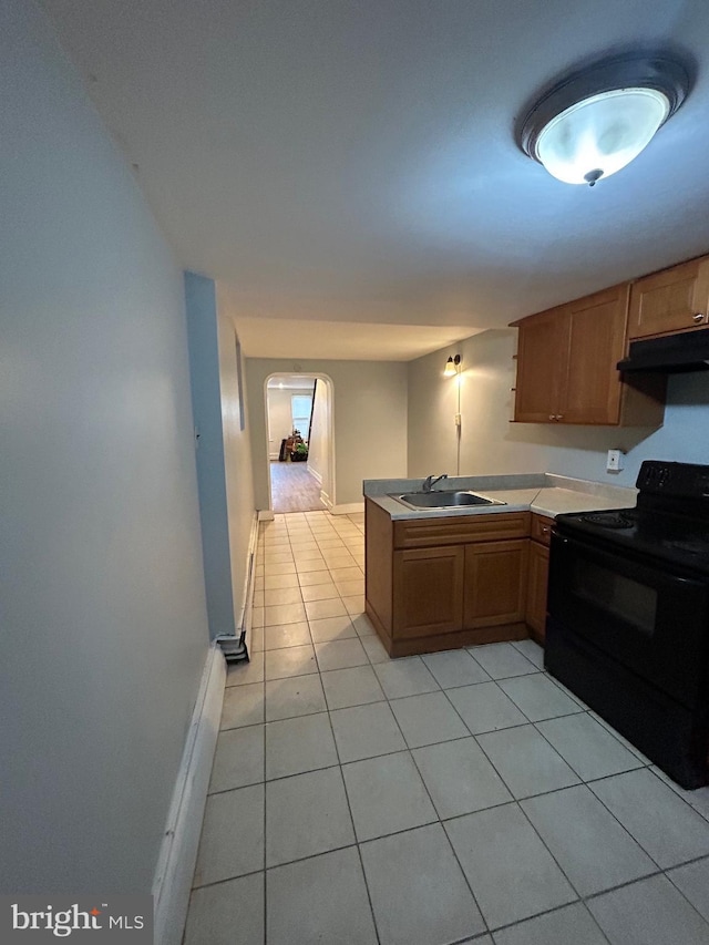 2229 Memphis St, Philadelphia, PA 19125 - kitchen featuring black / electric stove, under cabinet range hood, light tile patterned floors, arched walkways, and a sink