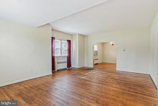 218 N Hammonds Ferry Rd, Linthicum Heights, MD 21090 - spare room featuring radiator, arched walkways, wood finished floors, and baseboards
