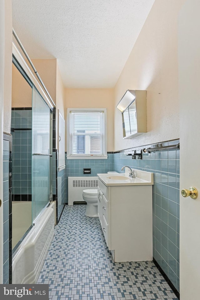 218 N Hammonds Ferry Rd, Linthicum Heights, MD 21090 - full bathroom with radiator, tile walls, toilet, vanity, and combined bath / shower with glass door