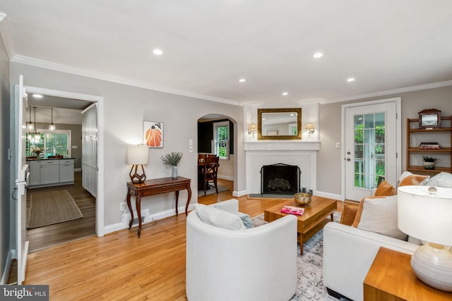 511 Wilton Rd, Towson, MD 21286 - living room with ornamental molding, arched walkways, light wood-style floors, a brick fireplace, and baseboards